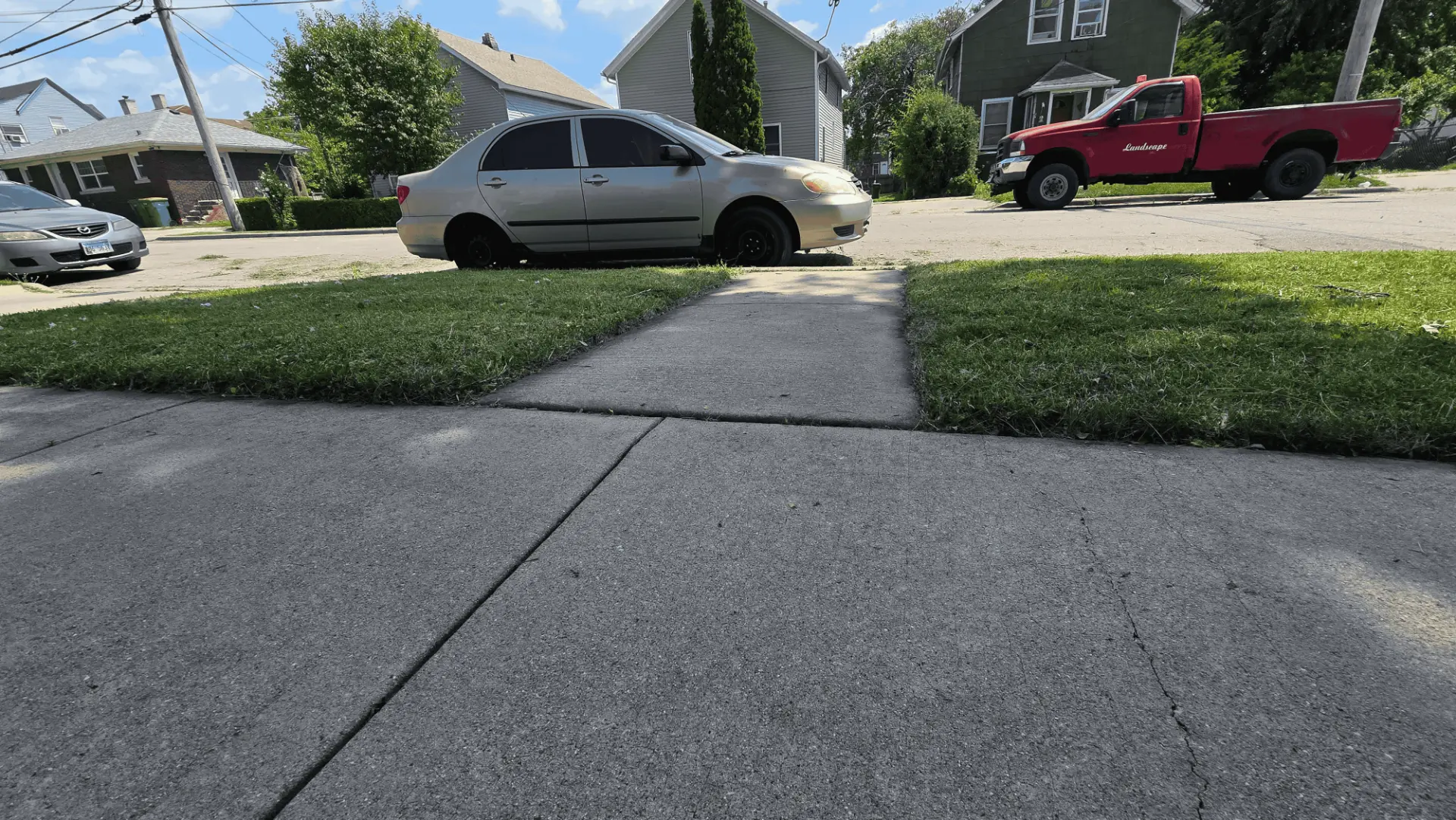 Neatly cut front lawn and clean sidewalk with the VOC landscape truck parked on the street